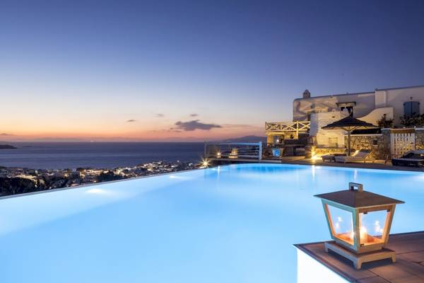 Abendlicher Blick auf den Pool des Vencia Boutique Hotels mit Meer und Stadt im Hintergrund.