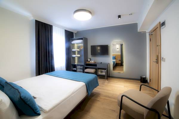 Innenansicht eines Zimmers im Barin Hotel mit Bett, Schreibtisch und Fernseher.
