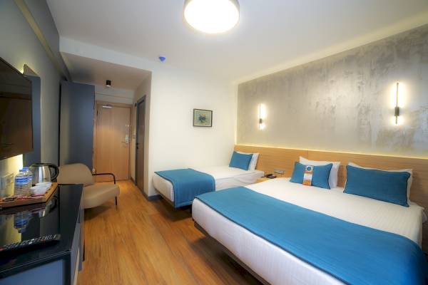 Doppelzimmer im Barin Hotel mit zwei Betten, Fernseher und Nachttisch.