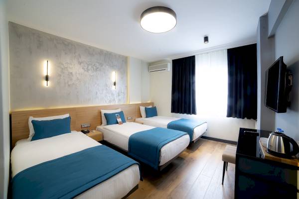 Drei Betten im Hotelzimmer mit blauen Decken und weißen Kissen.