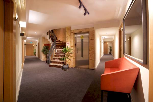 Flur des Barin Hotels mit einem roten Sofa und Pflanzen neben einer Treppe und einem Aufzug.