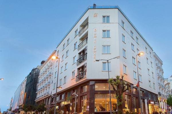 Außenansicht des Barin Hotels bei Nacht, ein weißes Gebäude mit vielen Fenstern und leuchtenden Straßenlaternen.