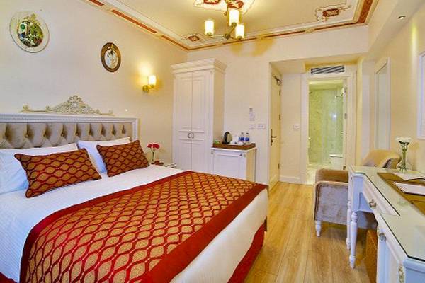 Innenansicht eines luxuriösen Hotelzimmers im Yilsam Sultanahmet Hotel, mit Bett, Schreibtisch und Badezimmer.