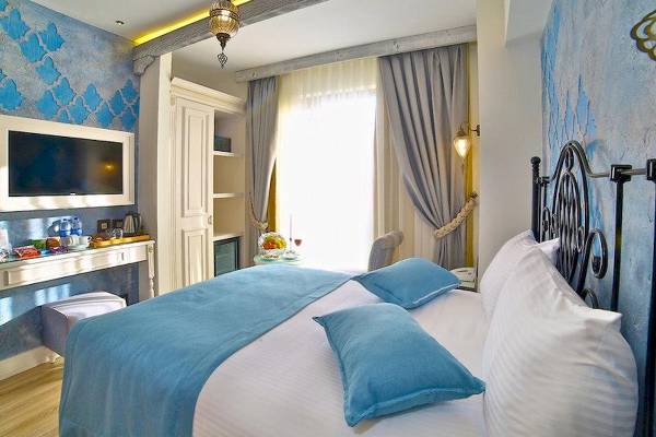 Yilsam Sultanahmet Hotel Zimmer mit blauen Wänden, einem Bett und einem Fernseher.