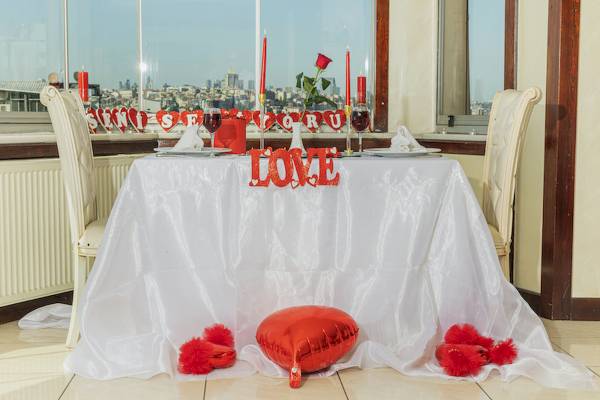 Ein romantisches Valentinstags-Dinner-Setup im Ipek Palas Hotel mit einem Tisch, der mit einem weißen Tischtuch und roten Herzen dekoriert ist.