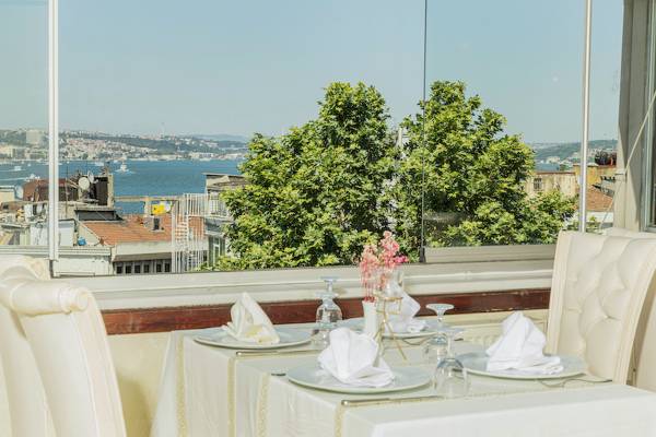 Restauranttisch im Ipek Palas Hotel mit Blick auf das Meer und Bäume.