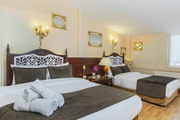Doppelzimmer im Ipek Palas Hotel mit zwei Betten, Nachttischen, Lampen und Dekor an den Wänden.