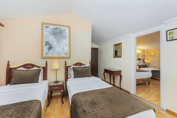 Zwei Betten in einem Schlafzimmer des Ipek Palas Hotels, mit einem Nachttisch und einer Lampe.