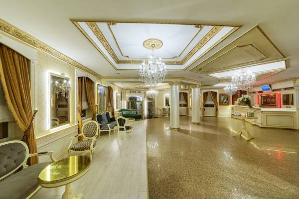 Empfangsbereich des Ipek Palas Hotels mit luxuriösem Design, Kristallkronleuchtern, weißen Böden und eleganten Möbeln.