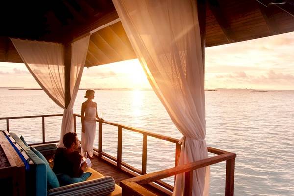 Sonnenuntergang auf der Terrasse des Hotels Sun Siyam Iru Fushi mit einem Paar, das den Blick auf das Meer genießt.