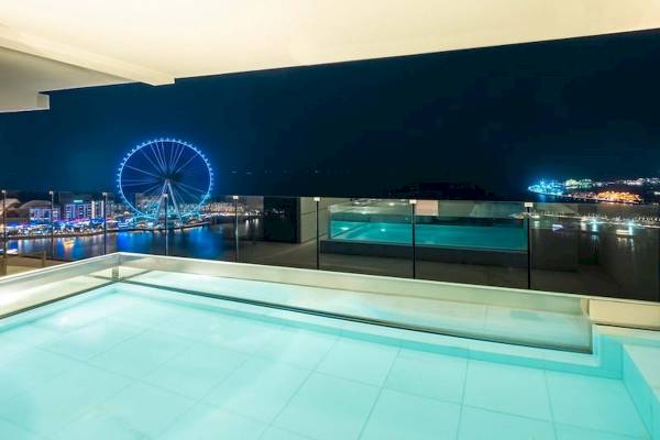 Nachtliche Aussicht auf das Meer mit beleuchtetem Riesenrad im Hintergrund im FIVE LUXE JBR