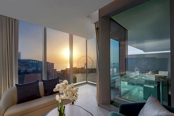 Innenansicht der Suite im FIVE LUXE JBR mit Blick auf eine Stadt und einen Whirlpool.
