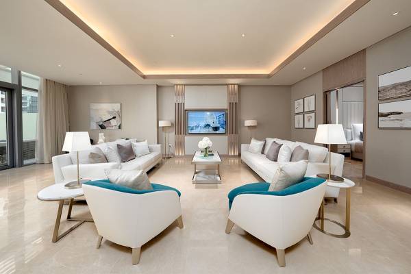 Luxus Wohnzimmer im FIVE LUXE JBR mit weißen Möbeln, einem Fernseher und einem Tisch mit einer Blumenvase.