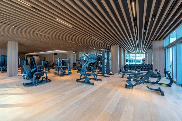Fitnesscenter im Five Luxe JBR Hotel mit modernen Geräten und Holzboden.