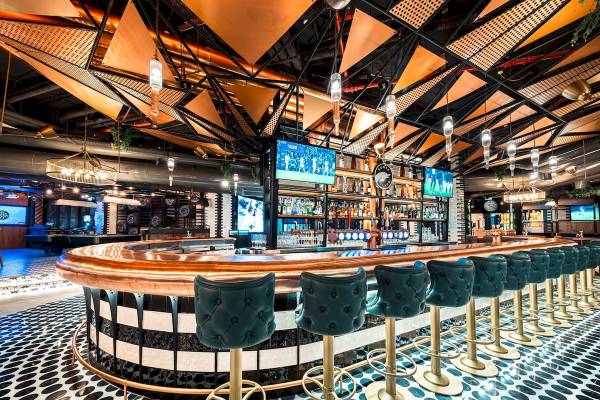 Innenansicht der Bar im FIVE LUXE JBR Hotel mit grünen und goldenen Barhockern und einer Theke.