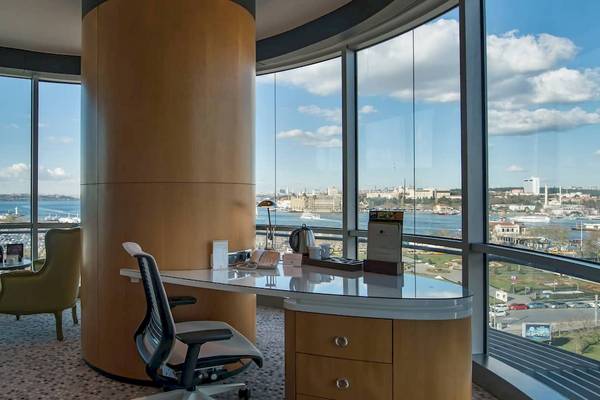 Innenansicht eines Zimmers im Doubletree by Hilton Istanbul Moda mit Schreibtisch, Stühlen und Panoramafenstern.