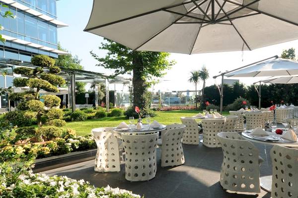 Gartenbereich des Doubletree by Hilton Istanbul Moda mit Tischen und Stühlen unter Schirmen.