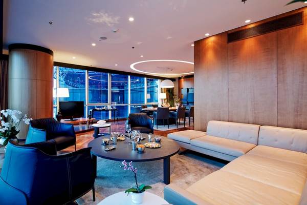 Wohnzimmer im Doubletree by Hilton Istanbul Moda mit Möbeln, Fernseher, Blumen und großer Fensterfront.