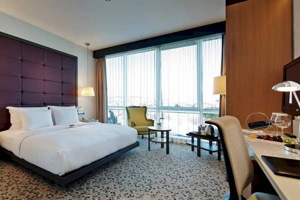 Doppelzimmer im Doubletree by Hilton Istanbul Moda Hotel mit großem Bett, Schreibtisch, Sessel und Fenstern.