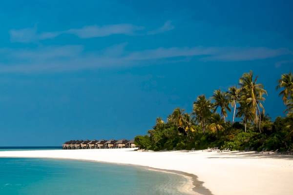 Sonnenaufgang am Strand des Sun Siyam Iru Fushi Hotels mit weißen Sand und blauem Meer.