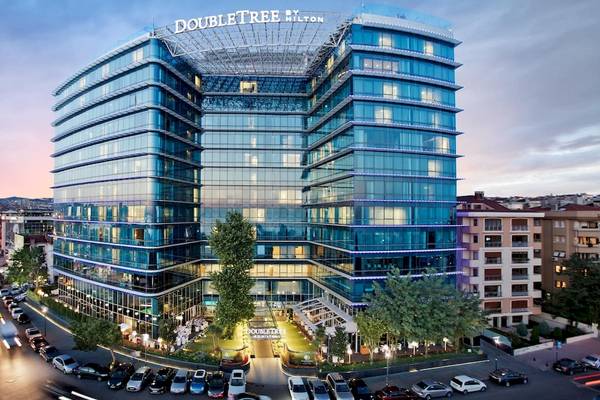 Außenansicht des Doubletree by Hilton Istanbul Moda Hotels mit vielen geparkten Autos vor dem Gebäude.