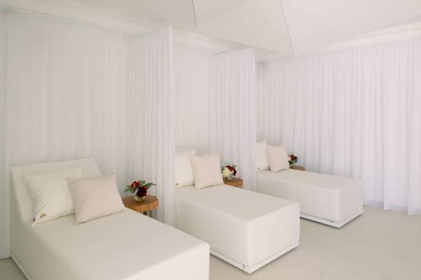 Weißes Hotelzimmer von L'Hostellerie du Moulin mit drei weißen Betten und weißen Vorhängen.