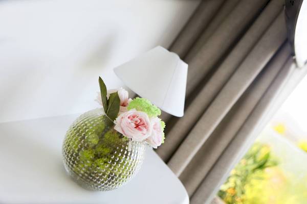 Blumen in einem Glas auf einem Tisch neben einer weißen Lampe.