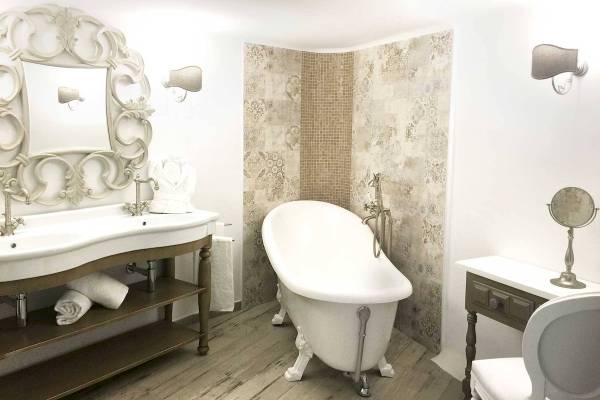 Badezimmer in L'Hostellerie du Moulin mit Badewanne, Waschbecken und dekorativen Wandfliesen.