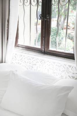 Ein Bett mit weißen Kissen und einem Fenster im Hintergrund im Hotel L'Hostellerie du Moulin