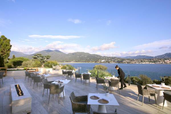 Außenterrasse des L'Hostellerie du Moulin Hotels mit Blick auf das Meer und Berge.