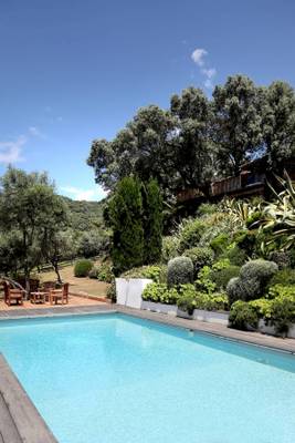 Außenbereich des L'Hostellerie du Moulin Hotels mit Swimmingpool, Holzmöbeln und umliegenden Gärten.
