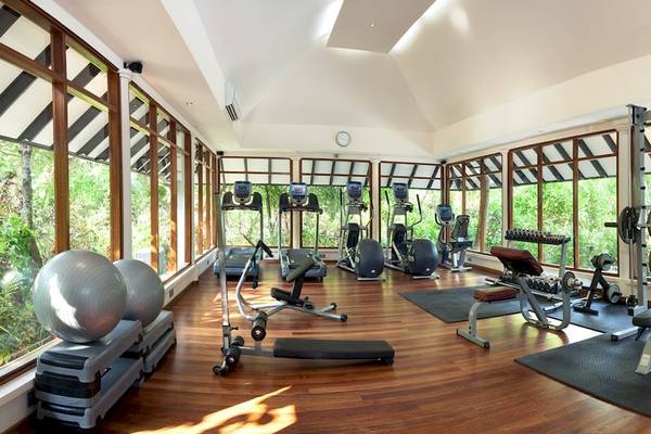 Fitnesscenter im Hotel Sun Siyam Iru Fushi mit Geräten und Blick auf den Garten.