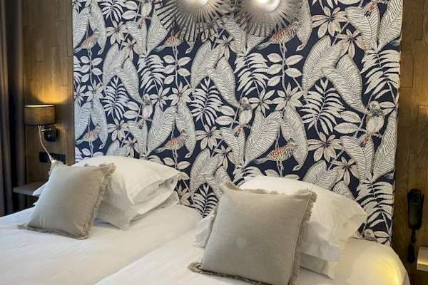 Doppelbett im La Lagune Hotel mit tropischem Wanddesign und Lampen