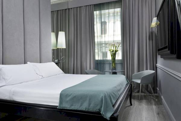 Schlafzimmer im Leon's Place Hotel mit Bett, Stühlen, Tisch und Fernseher.
