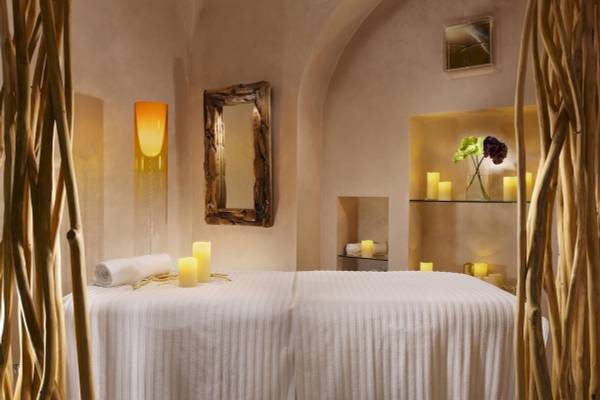 Spa-Behandlungsraum im Leon's Place Hotel mit weißen Laken, Kerzen und natürlichen Dekorelementen.