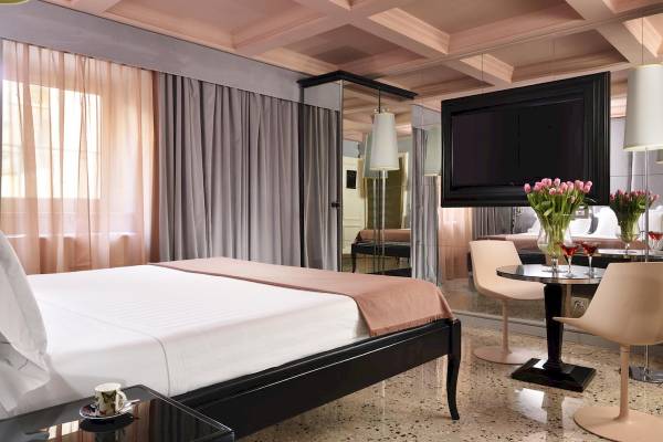 Leon's Place Hotelzimmer mit Bett, Tisch und Spiegeln, Blumen und Fernseher