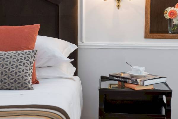 Schlafzimmer im Bettoja Hotel Mediterraneo mit Bett, Kissen, Nachttisch und Lampe.