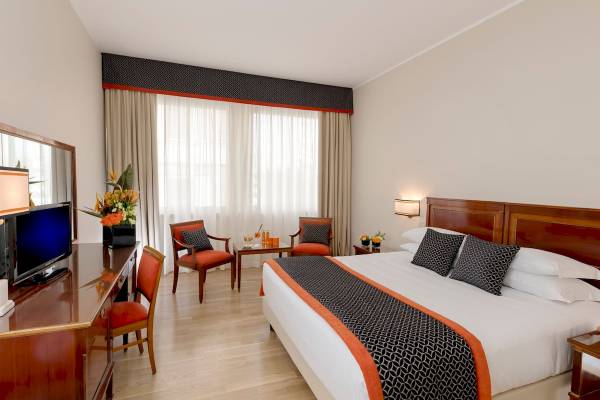 Zimmer im Bettoja Hotel Mediterraneo mit Doppelbett, Fernseher und Dekor.