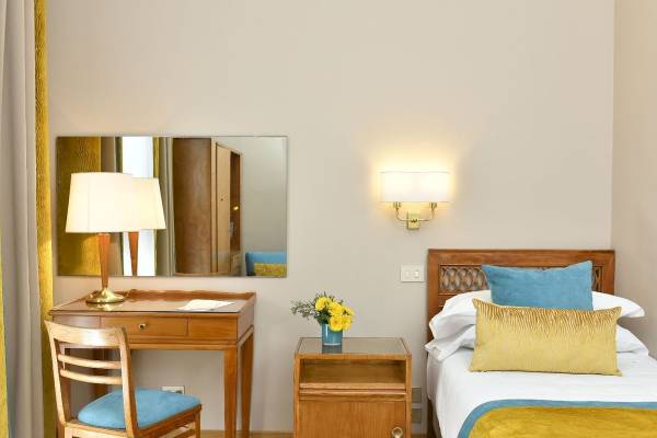 Schlafzimmer im Bettoja Hotel Mediterraneo mit Bett, Schreibtisch, Stuhl, Lampe und Blumen.