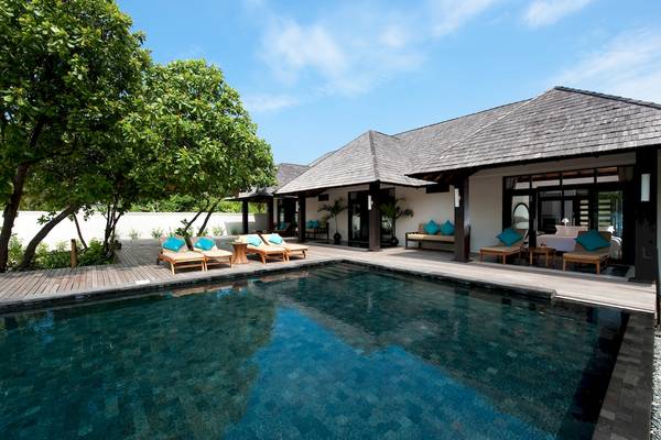 Außenpoolbereich des Sun Siyam Iru Fushi Hotels mit Loungestühlen und Bäumen.