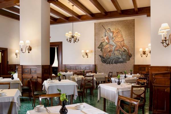 Innenansicht des Restaurants im Bettoja Hotel Mediterraneo mit gedeckten Tischen und Wandgemälde.