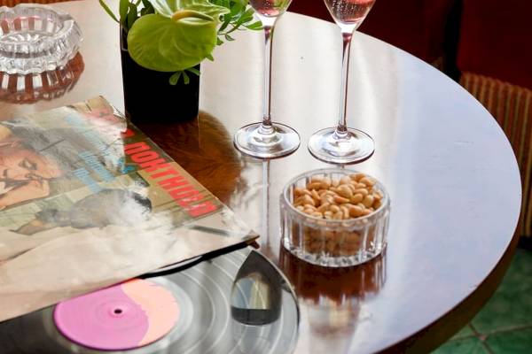 Tisch im Bettoja Hotel Mediterraneo mit zwei Gläsern, einer Nussschale und einer Vinyl-Scheibe.