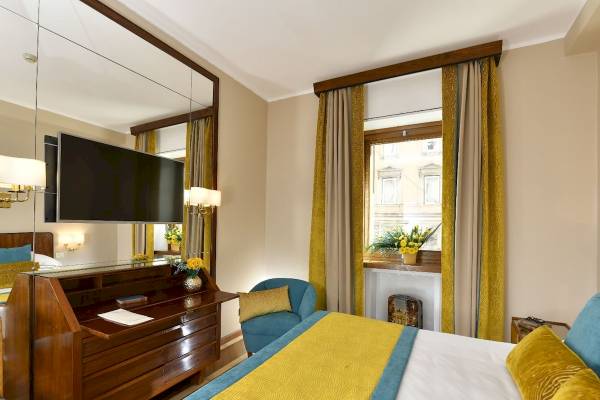 Schlafzimmer im Bettoja Hotel Mediterraneo mit großem Bett, Fernseher, Schreibtisch und Fenstern.