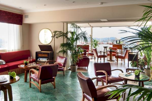 Lobby des Bettoja Hotel Mediterraneo mit roten Stühlen, Tischen und Pflanzen.