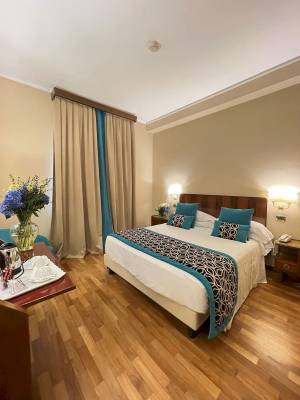 Hotelzimmer im Bettoja Hotel Mediterraneo mit Bett, Tisch und Blumen.