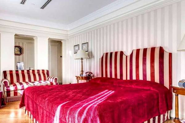Schlafzimmer im Bettoja Hotel Mediterraneo mit rotem Bett und gestreiften Kopfteil.