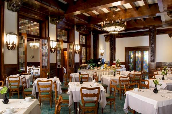 Innenansicht des Restaurants im Bettoja Hotel Mediterraneo mit gedeckten Tischen und Holzmöbeln.