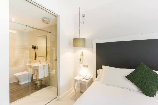 Badezimmer im ARTIEM Audax Hotel mit Glasdusche, Toilette und Waschbecken.