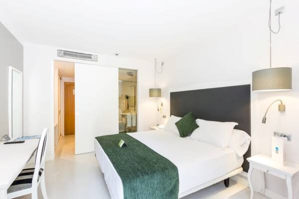 Innenansicht eines Zimmers im ARTIEM Audax Hotel mit einem großen Bett, einem Schreibtisch und Stühlen.