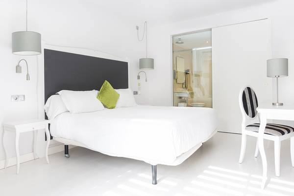 Weißes Schlafzimmer im ARTIEM Audax Hotel mit Bett, Nachttischen und Lampe.